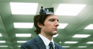 Personagem da série Ruptura (Severance) em ambiente de escritório clínico, refletindo a ruptura entre vida pessoal e profissional.