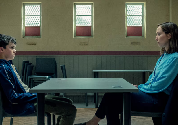 Cena da série Adolescência mostra a psicóloga Briony Ariston frente a frente com Jamie Miller, jovem investigado por homicídio, em um ambiente austero que representa a formalidade e a neutralidade da entrevista forense.