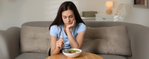 Jovem triste olhando para o prato, representando os desafios emocionais dos transtornos alimentares.