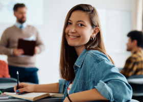 Profissional sorrindo ao começar sua primeira pós-graduação, em sala de aula.