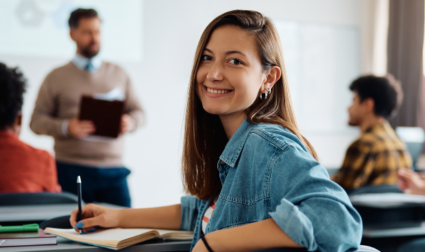 Profissional sorrindo ao começar sua primeira pós-graduação, em sala de aula.
